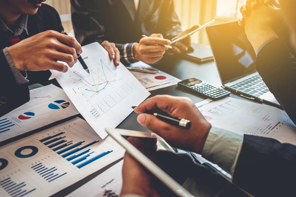Scène de travail en bureau avec personne analysant des documents financiers sur une table