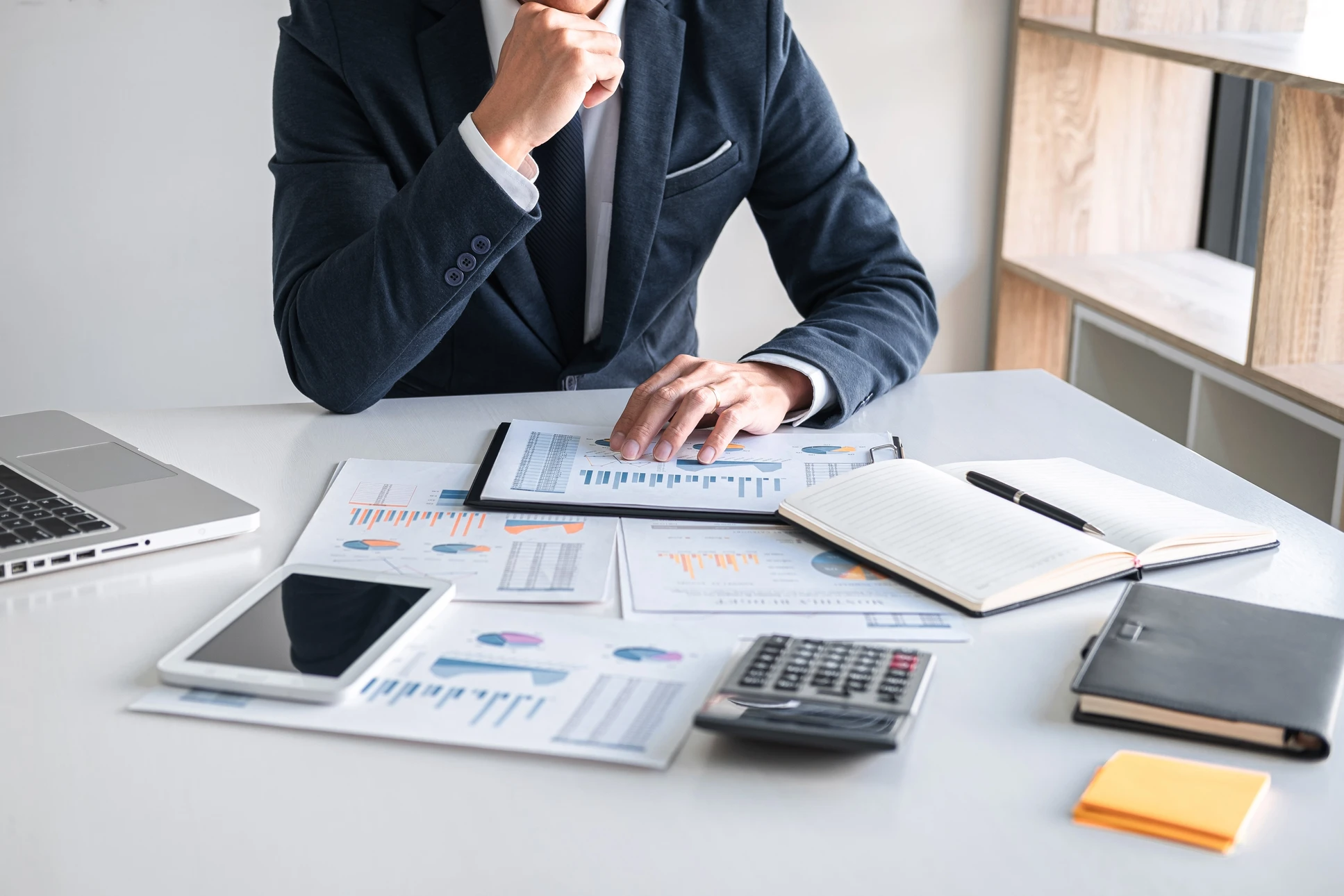 Un homme en costume analysant des documents financiers dans un bureau moderne